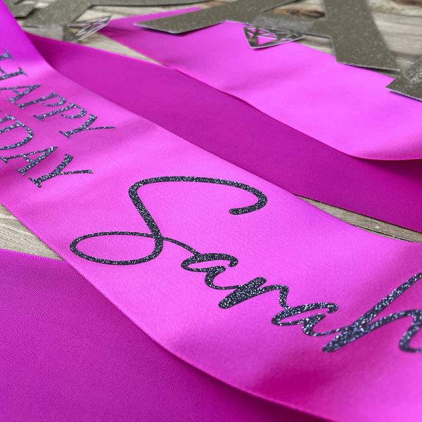 Close up of Silver Glitter Font on Pink Happy Birthday Sash